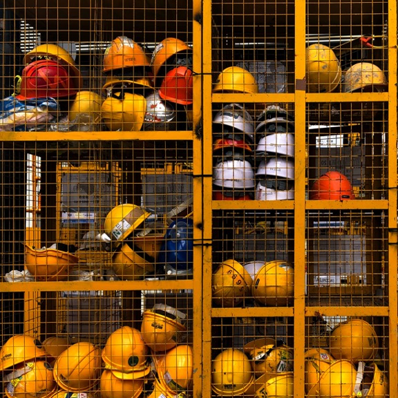 Yellow and red hardhats stored in a yellow locker.