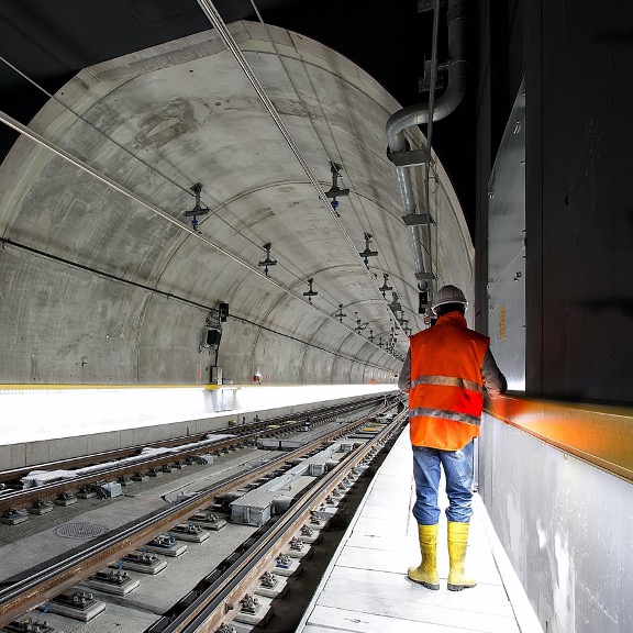Subway tunnel with a male worker wearing a high-visibility vest and hardhat.