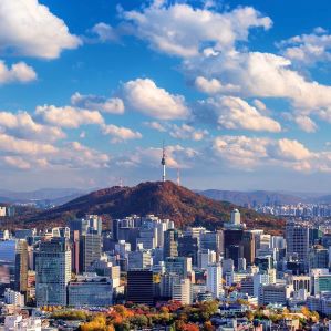 Seoul, South Korea, cityscape with mountain, blue sky, and clouds.