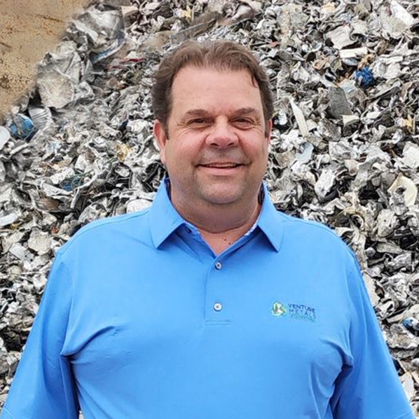 VP, Eric Kemp, headshot, against steel plate and pile of shredded aluminum scrap metal.